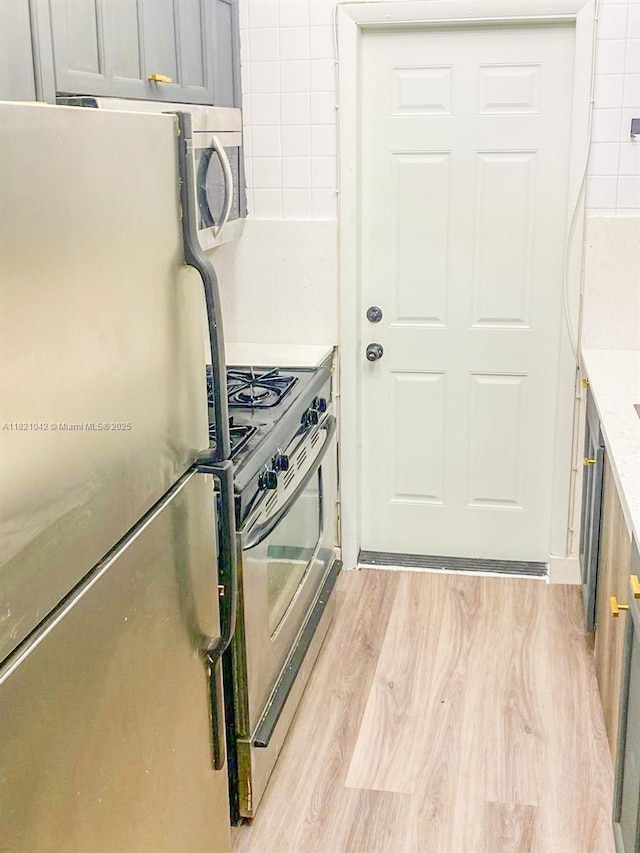 7720 Harding Ave Unit 3, Miami Beach, FL 33141 - kitchen featuring stainless steel appliances, light wood-style floors, and light countertops