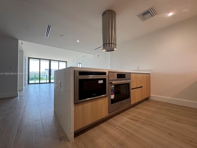 9901 W Bay Harbour Dr Unit 605, Bay Harbor Islands, FL 33154 - kitchen with stainless steel oven, light wood finished floors, modern cabinets, a wall of windows, and open floor plan