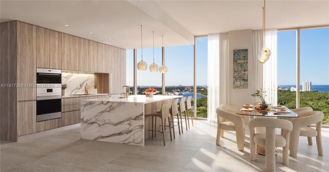 2901 NE 9th Ct Unit 6A, Fort Lauderdale, FL 33384 - kitchen with modern cabinets, floor to ceiling windows, stainless steel double oven, a large island with sink, and light stone countertops