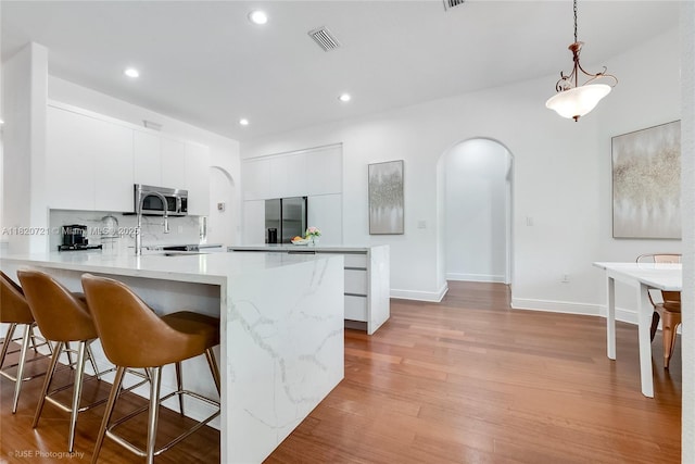 17050 SW 90th Ave, Palmetto Bay, FL 33157 - kitchen featuring stainless steel appliances, arched walkways, modern cabinets, a peninsula, and a kitchen breakfast bar
