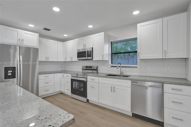 8511 NW 51st Ct, Lauderhill, FL 33351 - kitchen featuring stainless steel appliances, white cabinetry, light stone countertops, light wood finished floors, and backsplash