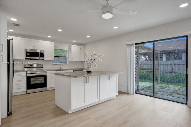 8511 NW 51st Ct, Lauderhill, FL 33351 - kitchen featuring appliances with stainless steel finishes, light wood-style flooring, white cabinetry, a ceiling fan, and a center island