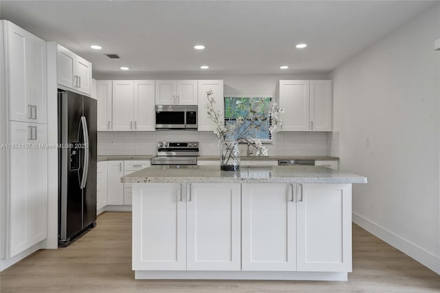 8511 NW 51st Ct, Lauderhill, FL 33351 - kitchen featuring stainless steel appliances, white cabinetry, decorative backsplash, a kitchen island, and light stone counters