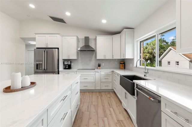 1020 SW 19th St SW, Naples, FL 34117 - kitchen featuring appliances with stainless steel finishes, wall chimney exhaust hood, decorative backsplash, white cabinets, and vaulted ceiling