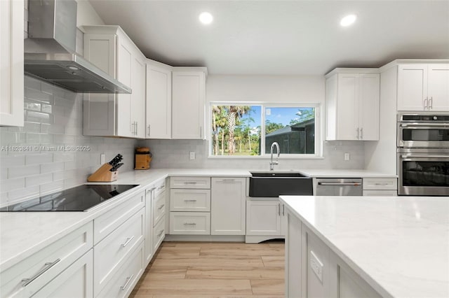 1020 SW 19th St SW, Naples, FL 34117 - kitchen with wall chimney exhaust hood, appliances with stainless steel finishes, recessed lighting, light countertops, and white cabinets