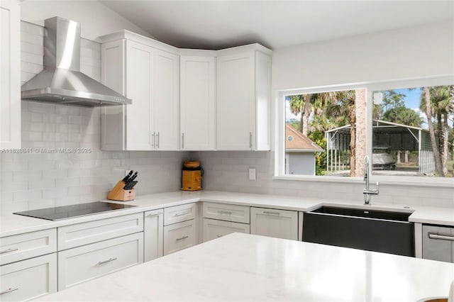 1020 SW 19th St SW, Naples, FL 34117 - kitchen with wall chimney exhaust hood, black electric stovetop, backsplash, and white cabinetry