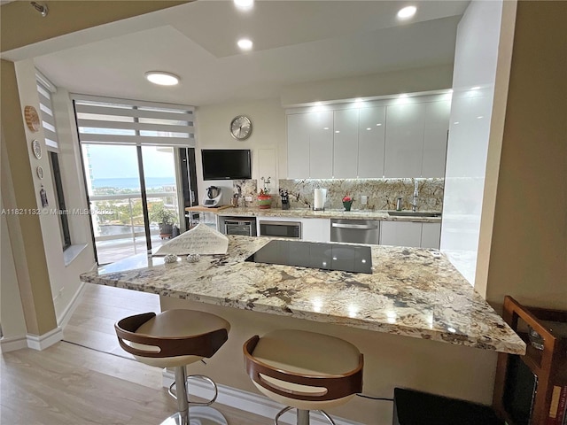 20191 E Country Club Dr Unit 1903, Aventura, FL 33180 - kitchen with appliances with stainless steel finishes, white cabinets, modern cabinets, a breakfast bar, and a wall of windows