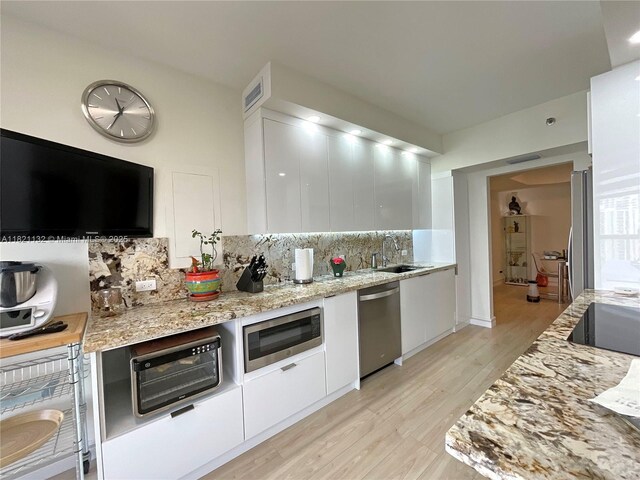 20191 E Country Club Dr Unit 1903, Aventura, FL 33180 - kitchen featuring stainless steel appliances, white cabinetry, tasteful backsplash, light wood-style floors, and modern cabinets