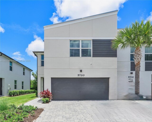 5720 Mentmore Dr, Mangonia Park, FL 33407 - contemporary house featuring an attached garage, driveway, and stucco siding