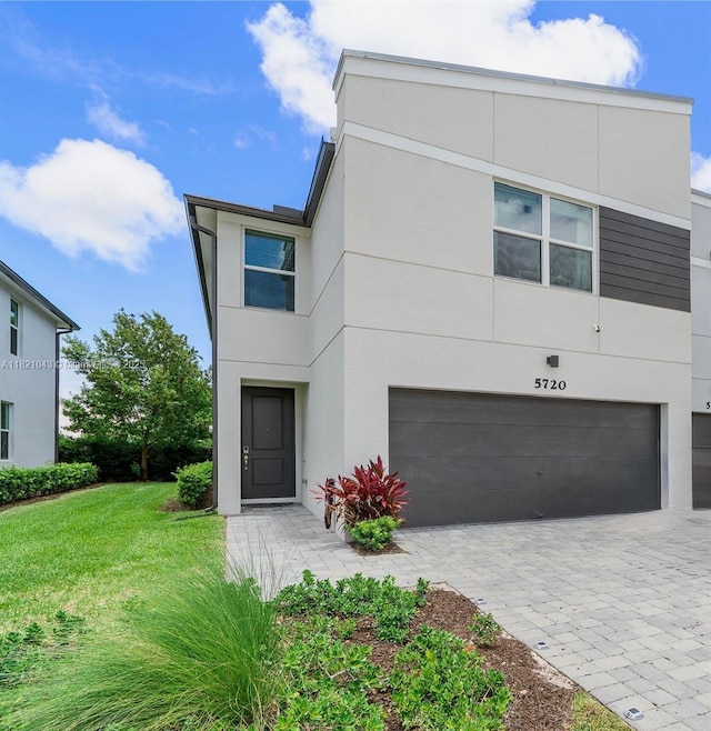 5720 Mentmore Dr, Mangonia Park, FL 33407 - view of front facade with stucco siding, a garage, decorative driveway, and a front yard
