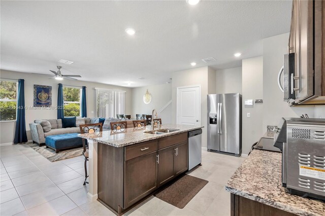 5720 Mentmore Dr, Mangonia Park, FL 33407 - kitchen with appliances with stainless steel finishes, open floor plan, a center island with sink, dark brown cabinetry, and a breakfast bar area