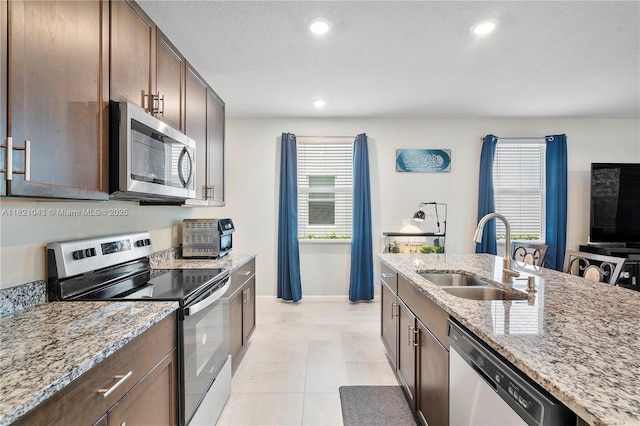 5720 Mentmore Dr, Mangonia Park, FL 33407 - kitchen with appliances with stainless steel finishes, light stone countertops, light tile patterned floors, recessed lighting, and dark brown cabinetry