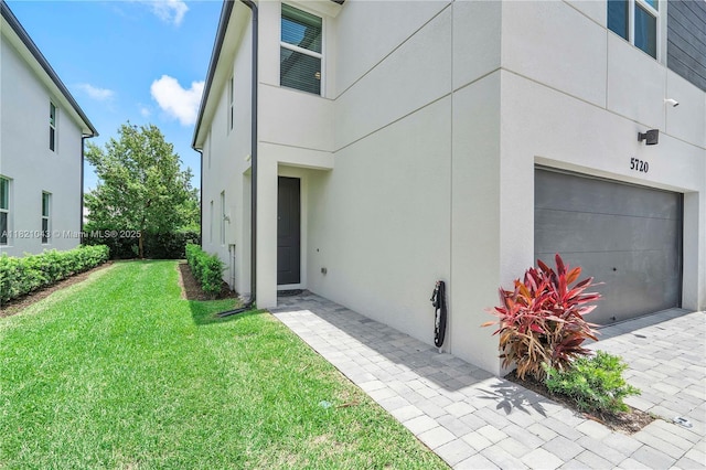 5720 Mentmore Dr, Mangonia Park, FL 33407 - doorway to property with an attached garage, a yard, and stucco siding