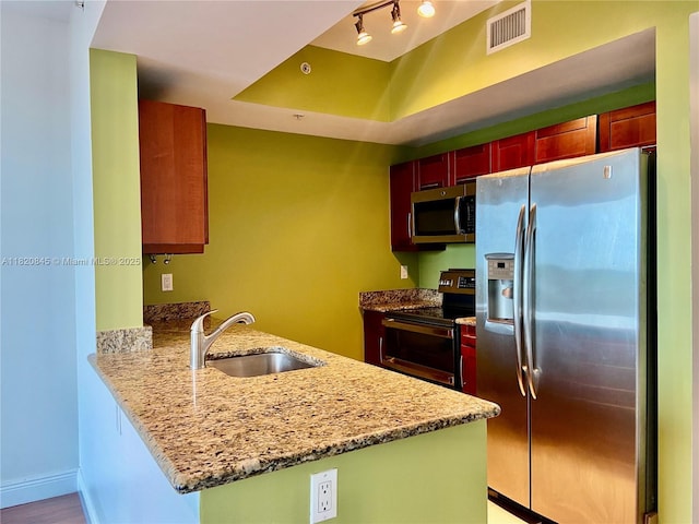 7275 SW 90th Way Unit 405, Miami, FL 33156 - kitchen featuring appliances with stainless steel finishes, a peninsula, dark brown cabinets, light stone counters, and track lighting