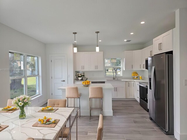21475 Argosy Ave, Port Charlotte, FL 33954 - kitchen with appliances with stainless steel finishes, white cabinetry, a breakfast bar, recessed lighting, and light wood-style flooring