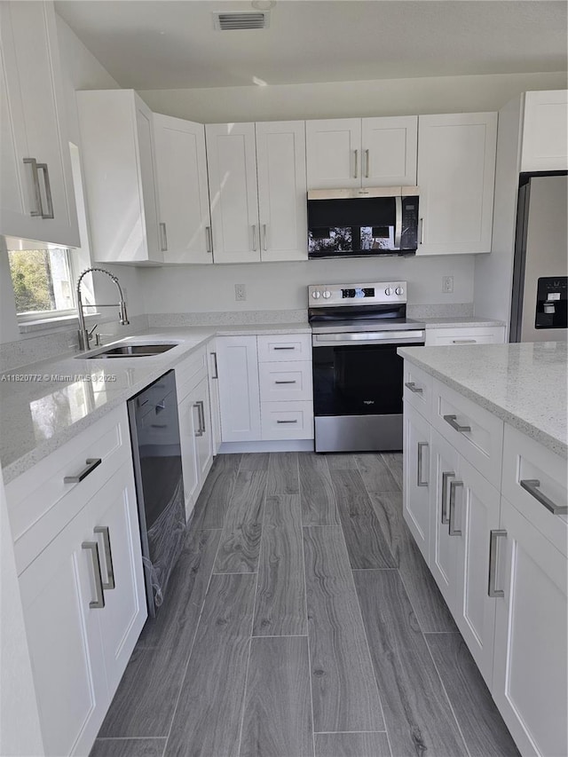 21475 Argosy Ave, Port Charlotte, FL 33954 - kitchen with stainless steel appliances, white cabinetry, and light stone countertops