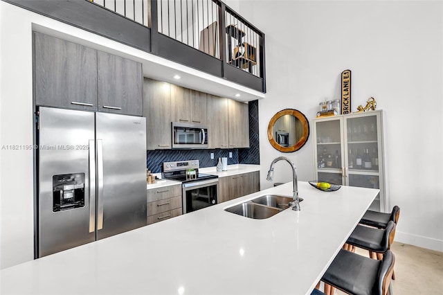 410 NE 36th St Unit 10, Oakland Park, FL 33334 - kitchen featuring appliances with stainless steel finishes, a kitchen breakfast bar, decorative backsplash, light countertops, and modern cabinets
