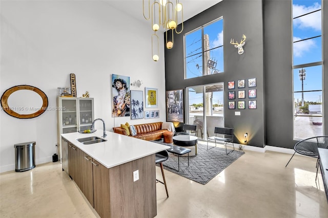 410 NE 36th St Unit 10, Oakland Park, FL 33334 - kitchen featuring finished concrete flooring, plenty of natural light, a towering ceiling, modern cabinets, and a kitchen island with sink