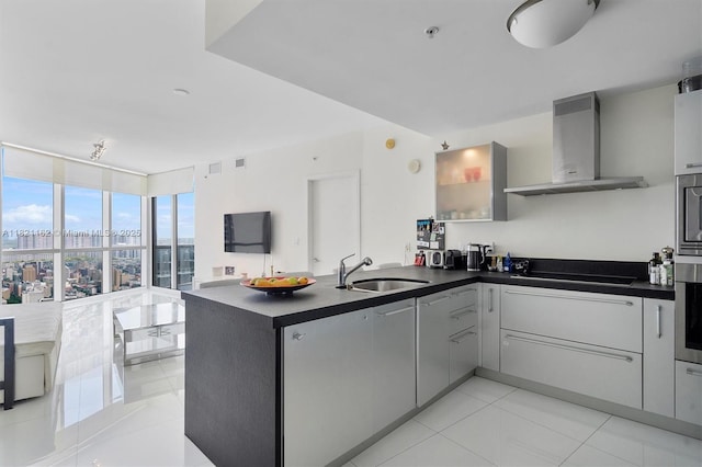 18201 Collins Ave Unit 2008, Sunny Isles Beach, FL 33160 - kitchen with wall chimney exhaust hood, a peninsula, dark countertops, light tile patterned floors, and floor to ceiling windows
