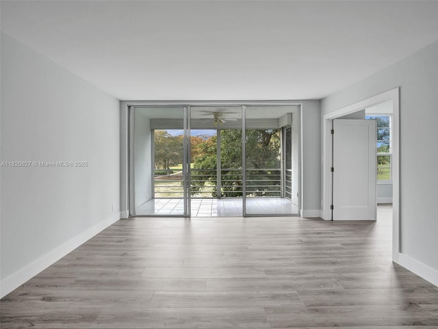 605 Oaks Dr Unit 309, Pompano Beach, FL 33069 - empty room featuring healthy amount of natural light, expansive windows, a ceiling fan, and wood finished floors