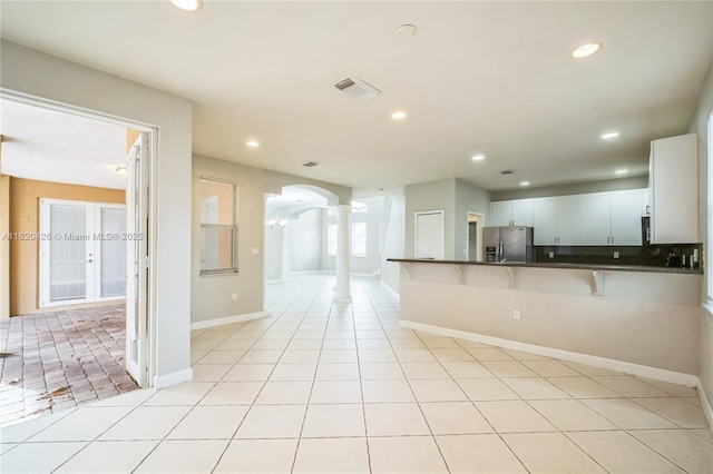 16313 SW 66th St, Miami, FL 33193 - kitchen featuring stainless steel refrigerator with ice dispenser, dark countertops, arched walkways, a breakfast bar, and ornate columns