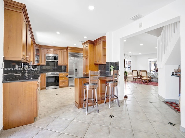 5343 NW 111th Ct, Doral, FL 33178 - kitchen with appliances with stainless steel finishes, a peninsula, tasteful backsplash, a kitchen breakfast bar, and dark countertops