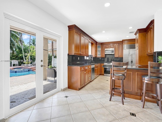 5343 NW 111th Ct, Doral, FL 33178 - kitchen with stainless steel appliances, decorative backsplash, dark countertops, light tile patterned floors, and recessed lighting