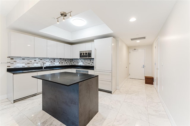 1010 Brickell Ave Unit 1409, Miami, FL 33131 - kitchen featuring stainless steel microwave, dark countertops, a raised ceiling, white cabinets, and light marble finish floors