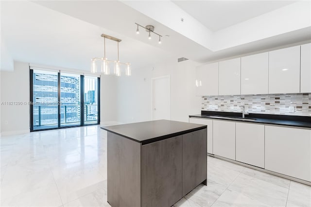1010 Brickell Ave Unit 1409, Miami, FL 33131 - kitchen featuring dark countertops, decorative backsplash, light marble finish flooring, and a wall of windows