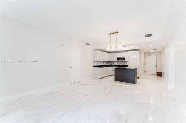 1010 Brickell Ave Unit 1409, Miami, FL 33131 - kitchen with stainless steel microwave, white cabinets, tasteful backsplash, open floor plan, and hanging light fixtures