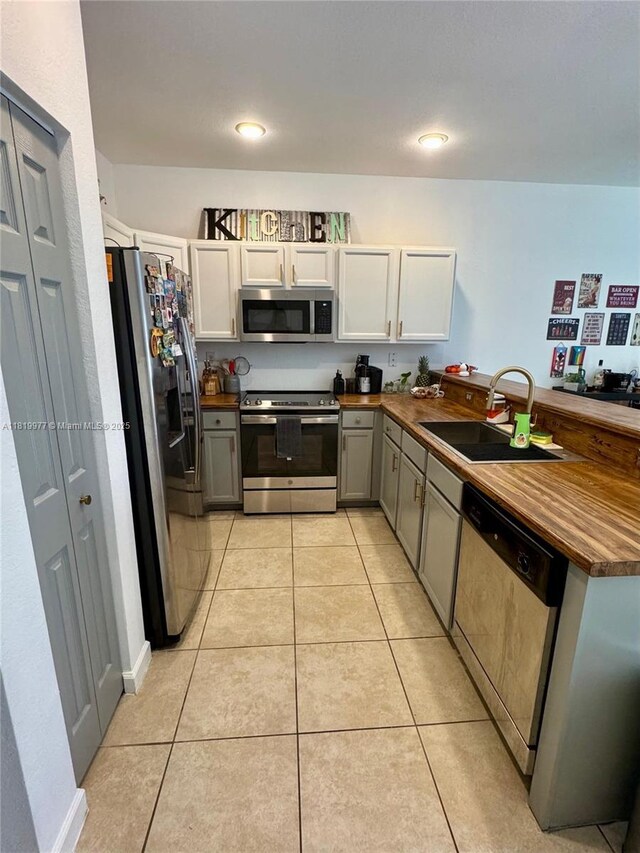 581 SE 32nd Ter, Homestead, FL 33033 - kitchen with stainless steel appliances, dark countertops, light tile patterned flooring, a peninsula, and gray cabinetry