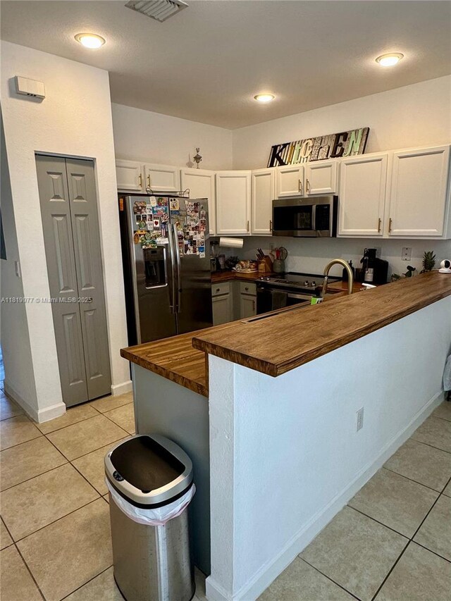 581 SE 32nd Ter, Homestead, FL 33033 - kitchen with stainless steel microwave, fridge with ice dispenser, butcher block countertops, a peninsula, and black range with electric stovetop