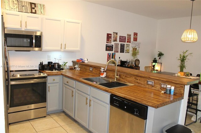 581 SE 32nd Ter, Homestead, FL 33033 - kitchen with appliances with stainless steel finishes, a peninsula, butcher block countertops, and light tile patterned flooring