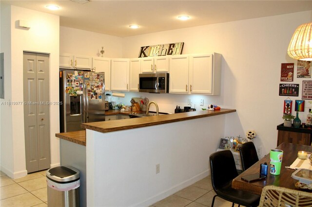 581 SE 32nd Ter, Homestead, FL 33033 - kitchen with stainless steel appliances, light tile patterned floors, wooden counters, a peninsula, and white cabinetry
