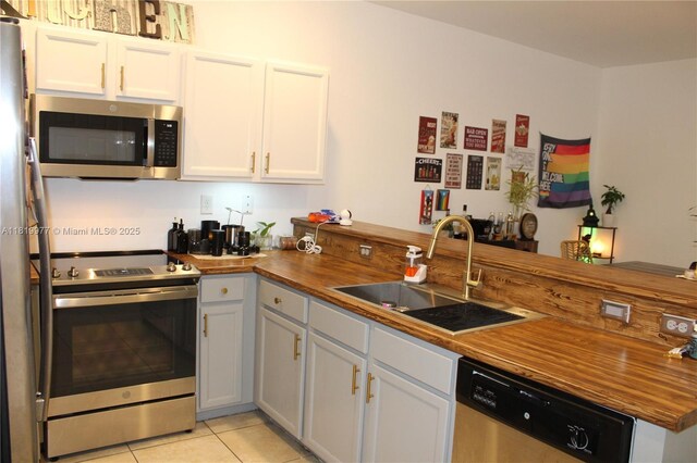 581 SE 32nd Ter, Homestead, FL 33033 - kitchen featuring stainless steel appliances, wooden counters, light tile patterned flooring, and white cabinets