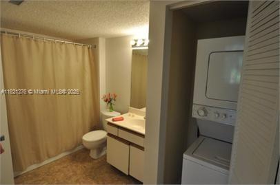 4055 W Mcnab Rd Unit H112, Pompano Beach, FL 33069 - bathroom featuring stacked washer and clothes dryer, vanity, and a textured ceiling