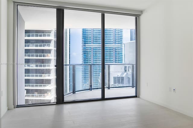 1000 Brickell Plz Unit 3703, Miami, FL 33131 - unfurnished room featuring healthy amount of natural light, wood finished floors, and a wall of windows