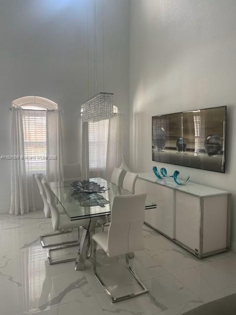 8770 SW 204th St, Cutler Bay, FL 33189 - dining area featuring light marble finish floors and a towering ceiling