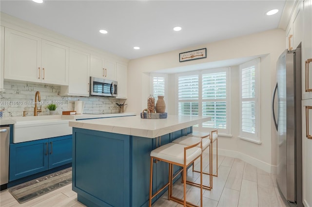 4034 N Ocean Dr, Hollywood, FL 33019 - kitchen with stainless steel appliances, blue cabinets, a breakfast bar, decorative backsplash, and recessed lighting