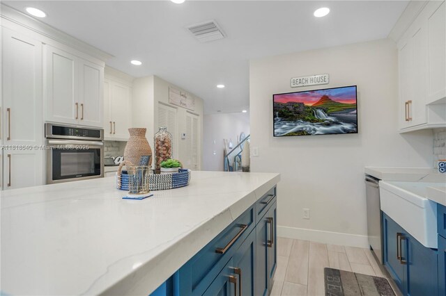 4034 N Ocean Dr, Hollywood, FL 33019 - kitchen with appliances with stainless steel finishes, blue cabinets, a kitchen island, light stone countertops, and backsplash