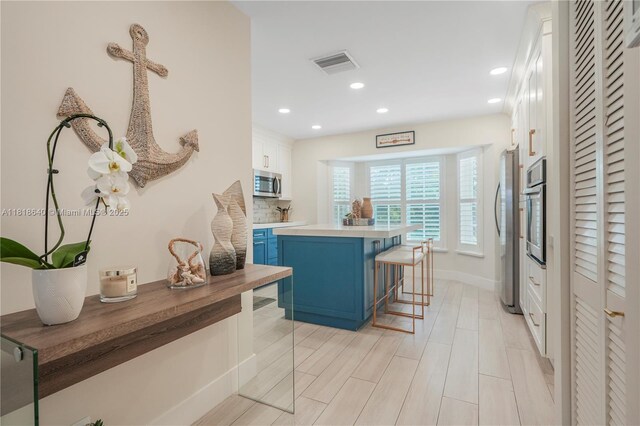4034 N Ocean Dr, Hollywood, FL 33019 - kitchen featuring stainless steel appliances, blue cabinetry, a kitchen breakfast bar, white cabinets, and recessed lighting