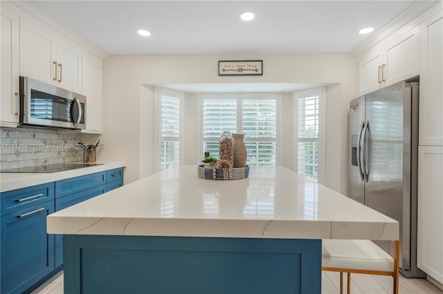 4034 N Ocean Dr, Hollywood, FL 33019 - kitchen featuring appliances with stainless steel finishes, blue cabinetry, a kitchen island, light stone counters, and decorative backsplash