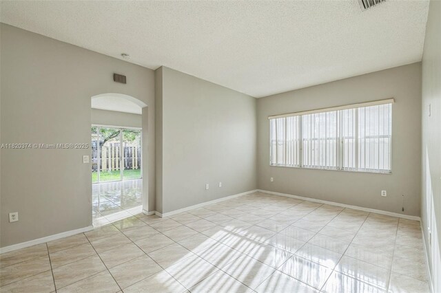 1951 NE 3rd Ct, Homestead, FL 33033 - unfurnished room with arched walkways, light tile patterned flooring, and a textured ceiling