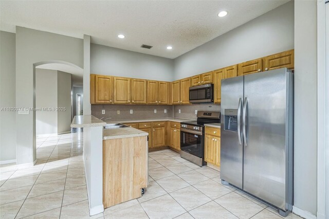 1951 NE 3rd Ct, Homestead, FL 33033 - kitchen featuring stainless steel appliances, arched walkways, a peninsula, light tile patterned floors, and recessed lighting