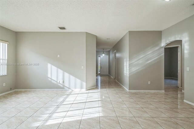 1951 NE 3rd Ct, Homestead, FL 33033 - spare room featuring light tile patterned flooring, a textured ceiling, and arched walkways