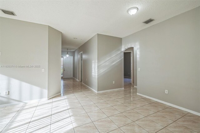 1951 NE 3rd Ct, Homestead, FL 33033 - empty room featuring arched walkways, light tile patterned flooring, and a textured ceiling