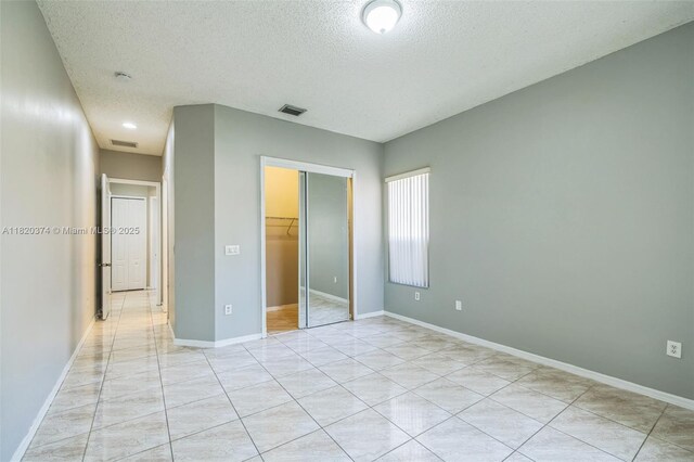 1951 NE 3rd Ct, Homestead, FL 33033 - unfurnished bedroom featuring a textured ceiling, a closet, and light tile patterned floors