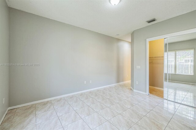 1951 NE 3rd Ct, Homestead, FL 33033 - empty room featuring a textured ceiling and light tile patterned flooring