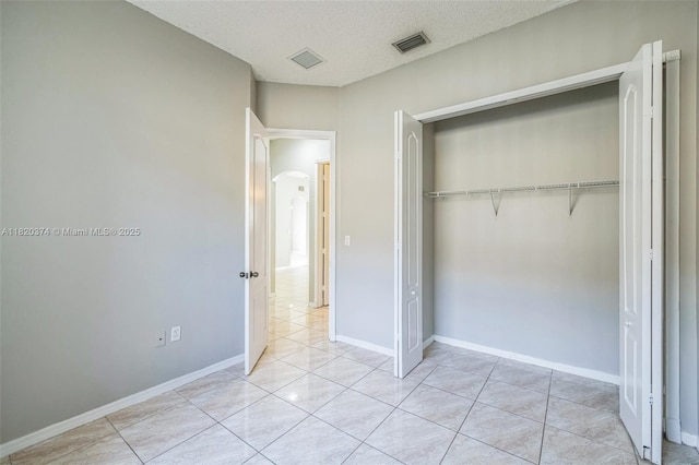 1951 NE 3rd Ct, Homestead, FL 33033 - unfurnished bedroom featuring a closet, arched walkways, light tile patterned floors, and a textured ceiling