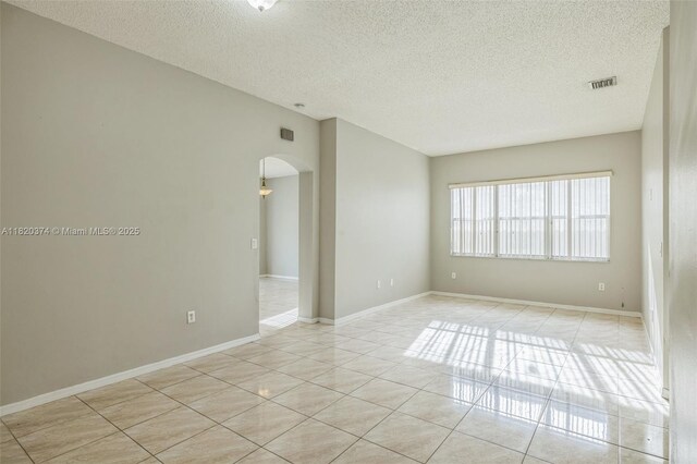1951 NE 3rd Ct, Homestead, FL 33033 - unfurnished room featuring a textured ceiling, arched walkways, and light tile patterned floors